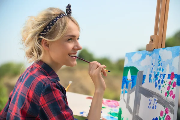 Piękna blond kobieta artysta maluje kolorowy obraz. — Zdjęcie stockowe