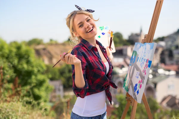 Vacker blond kvinna konstnär målar en färgglad bild. — Stockfoto