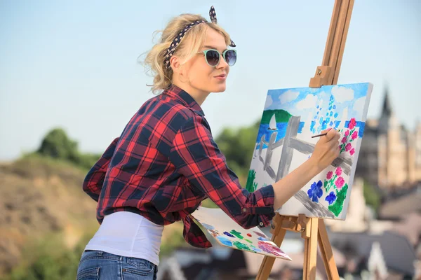 Linda artista mulher loira pinta uma imagem colorida . — Fotografia de Stock