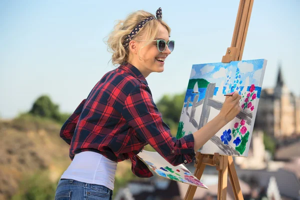Linda artista mulher loira pinta uma imagem colorida . — Fotografia de Stock