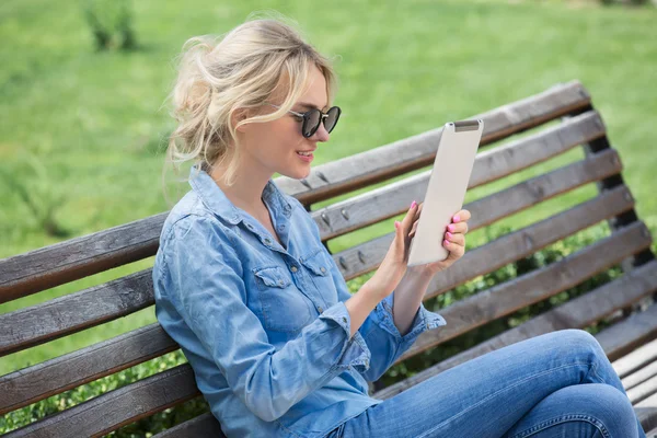 Mooie blonde vrouw met elektronische tablet in handen — Stockfoto