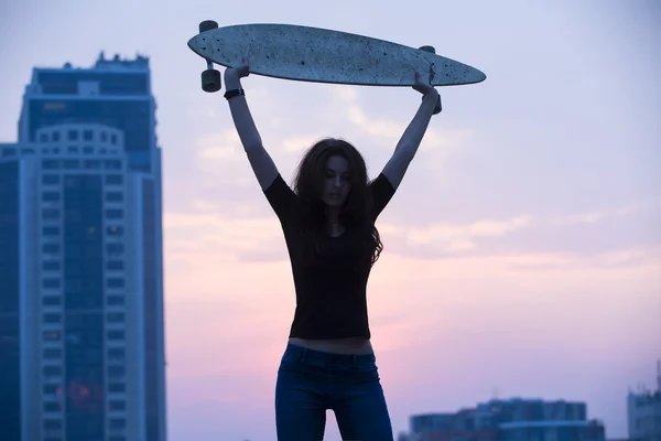 Κομψό κορίτσι με τζιν, κρατώντας ψηλά longboard — Φωτογραφία Αρχείου