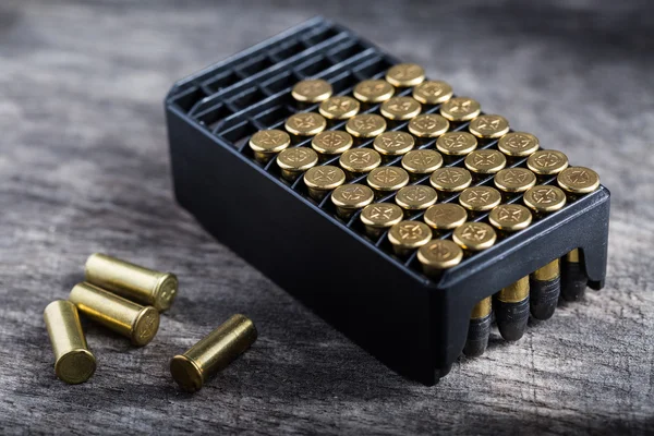 Scattering of small caliber cartridges on a wooden background — Stock Photo, Image