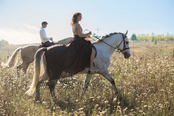 Pareja joven enamorada montando un caballo — Foto de Stock