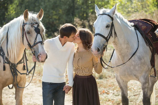 Casal jovem andando em um lugar pitoresco com cavalos — Fotografia de Stock