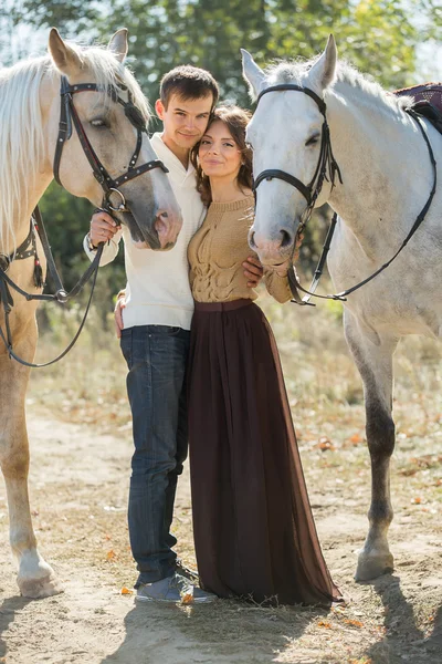 Pareja joven caminando en un lugar pintoresco con caballos —  Fotos de Stock