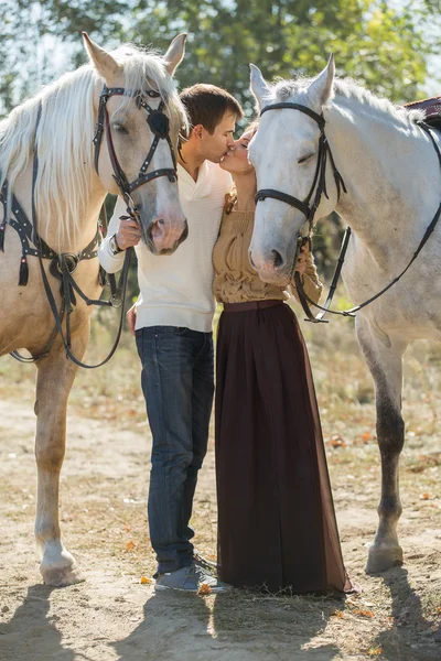 Casal jovem andando em um lugar pitoresco com cavalos — Fotografia de Stock