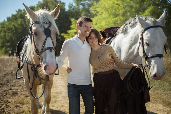 Young couple walking in a picturesque place with horses — Stock Photo, Image