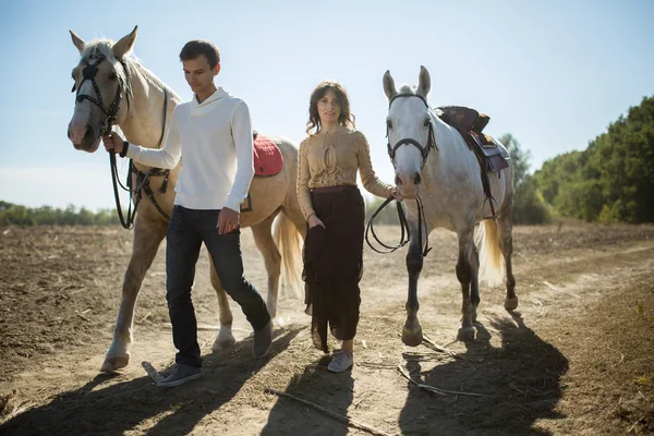 Pareja joven caminando en un lugar pintoresco con caballos —  Fotos de Stock