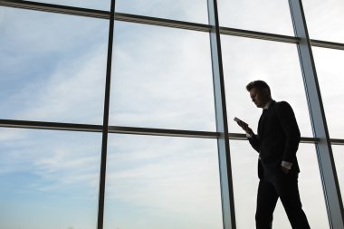 Büyük bir pencerenin arkasında şık bir iş adamı