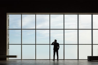 Büyük bir pencerenin arkasında şık bir iş adamı