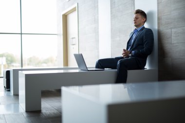 İşadamı dizüstü bilgisayarla bankta tek başına oturuyor.