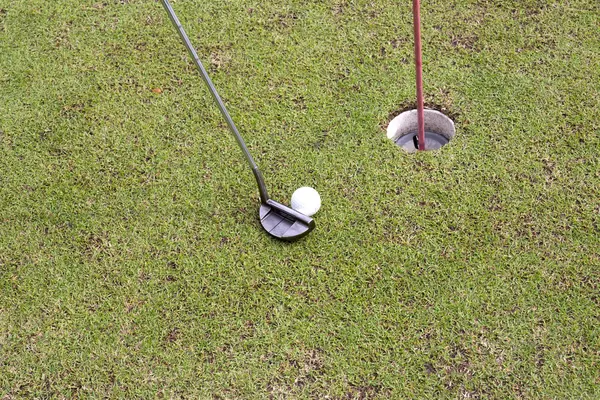 Jogador de golfe no putting green batendo bola em um buraco — Fotografia de Stock