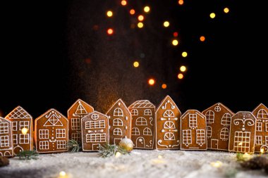 Pencerelerinden gelen ışığı, zencefilli kek şehrini, büyük yan ışıkları ve karı olan kış zencefilli kek evi. Yeni yıl içeriği. Noel kartı..