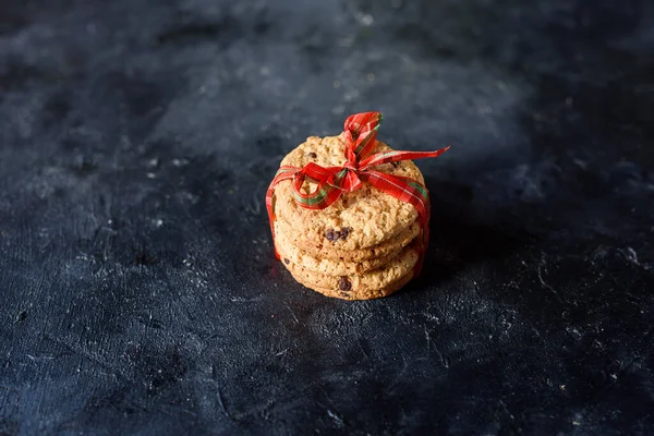 Pyszne ciasteczka typu shortbread z kawałkami czekolady, z piękną wstążką na ciemnym tle. Widok z góry — Zdjęcie stockowe