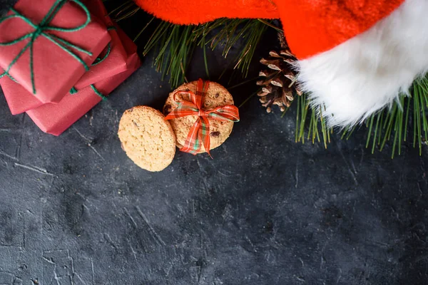 Deliciosas galletas de shortbread con trozos de chocolate, con cinta roja, una ramita de abeto, sombrero de Santas, un shortie sobre un fondo oscuro. — Foto de Stock