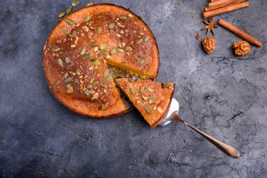 Limon aromalı balkabağı turtası, kabak tohumları, tarçın, kokulu baharatlar ve karanlık bir arka planda baharatlar. Sağlıklı ve lezzetli yemekler.