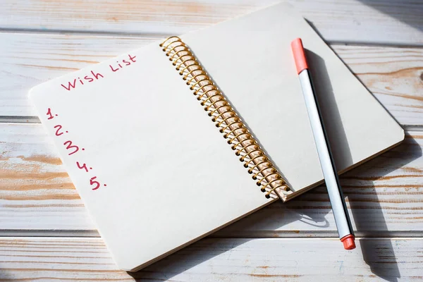 Boş çarşaflı not defteri ve dilek listemdeki kelimeler, sert gölgeler, kırmızı kalem. Noel Baba 'ya mektup, yeni yıl içeriği 2021