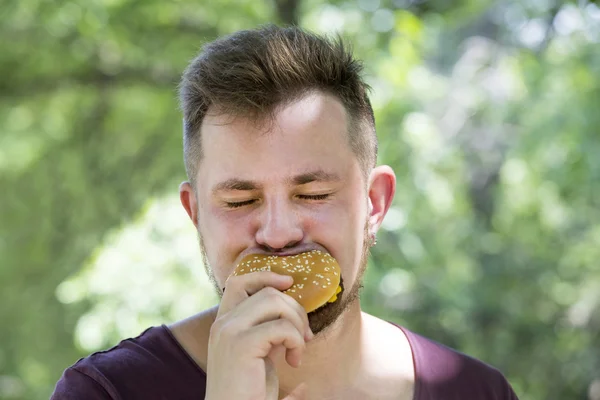 Hombre comiendo una hamburguesa —  Fotos de Stock