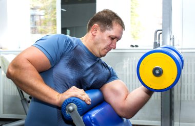 Sportif görünümlü yetişkin bir erkek spor salonunda vücut geliştirmekle meşgul..