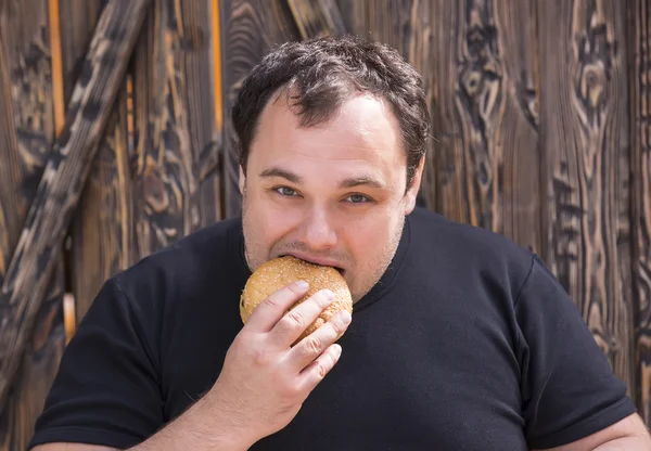 Brutal man eating a hamburger — Stock Photo, Image