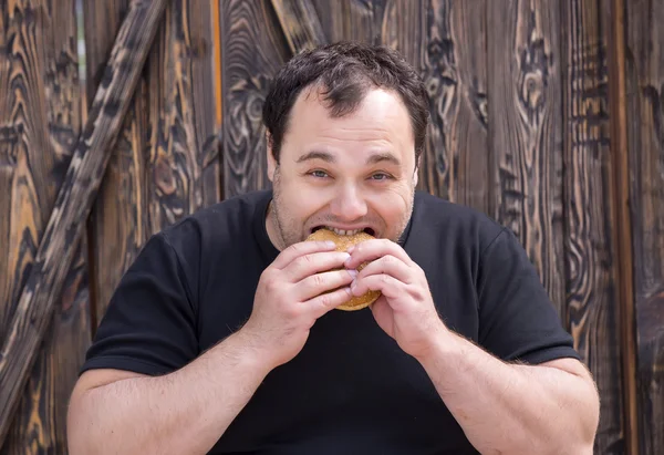 Hombre brutal comiendo una hamburguesa —  Fotos de Stock