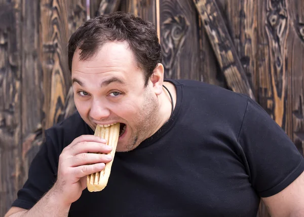 Brutal man eating a hot dog — Stock Photo, Image