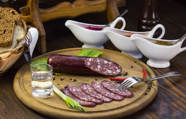 Sausages on a wooden plate with vegetables — Stock Photo, Image
