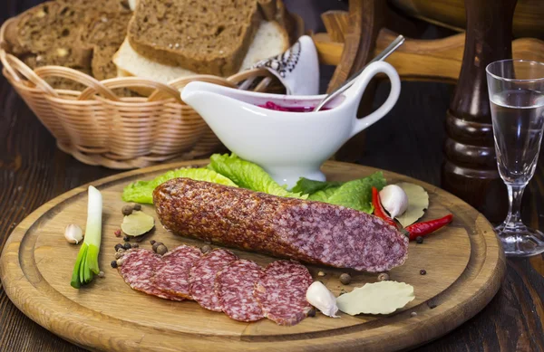 Sausages on a wooden plate with vegetables — Stock Photo, Image