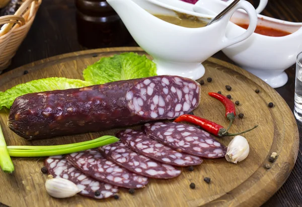 Sausages on a wooden plate with vegetables — Stock Photo, Image