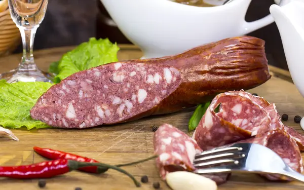 Sausages on a wooden plate with vegetables — Stock Photo, Image