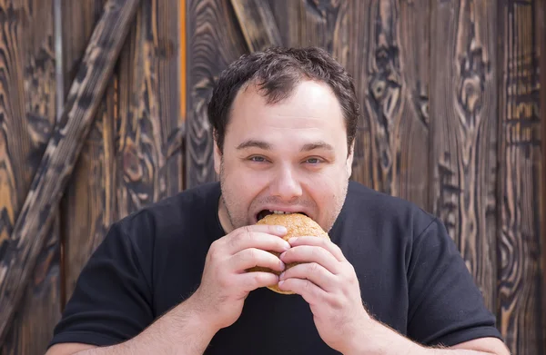 Hombre brutal comiendo una hamburguesa —  Fotos de Stock