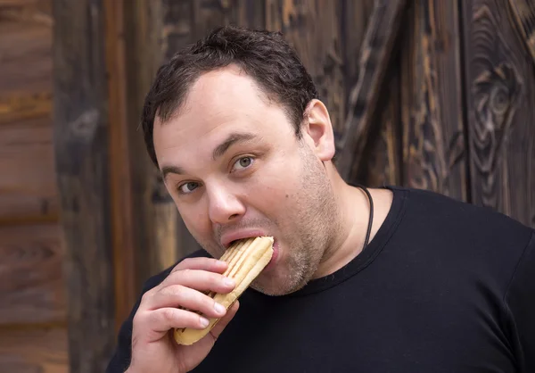 Brutal homem comendo um cachorro quente — Fotografia de Stock