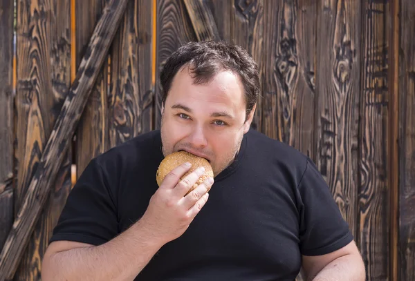 Hombre brutal comiendo una hamburguesa —  Fotos de Stock