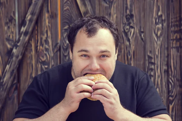 Hombre brutal comiendo una hamburguesa —  Fotos de Stock