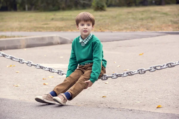 Młody chłopak siedzieć na łańcuch — Zdjęcie stockowe