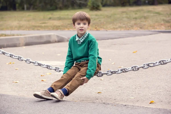 Young boy sit on chain — Stock Photo, Image