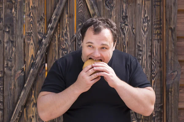Brutal man eating a hamburger — Stock Photo, Image