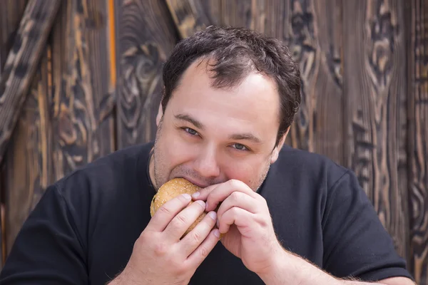 Brutal man eating a hamburger — Stock Photo, Image