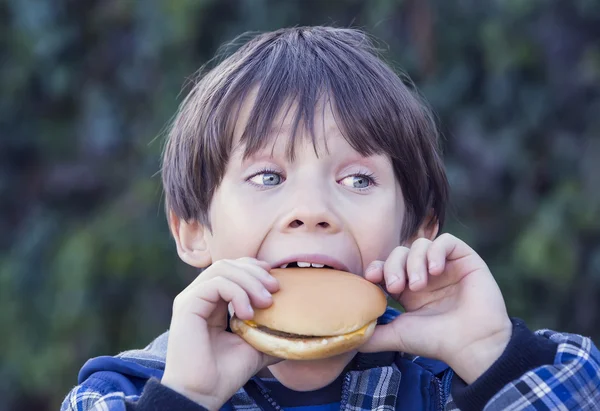 Niño comiendo una hamburguesa — Foto de Stock