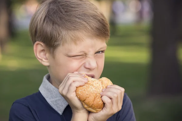 Pojken äta en hamburgare — Stockfoto