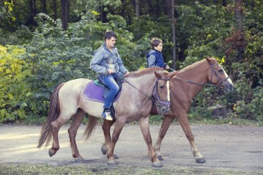 Father and son riding together on horses clipart