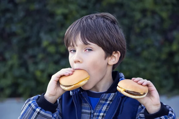 Мальчик ест гамбургеры — стоковое фото