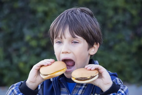 Мальчик ест гамбургеры — стоковое фото