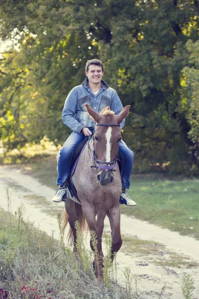 Jeune homme chevauchant cheval de race pure — Photo
