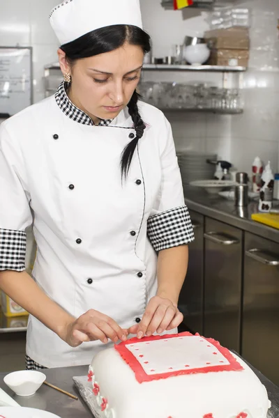 Pastry chef decorates a cake — Stock Photo, Image