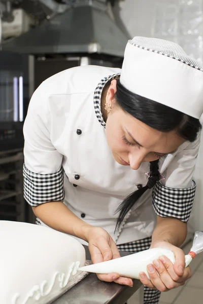 Chef de pastelaria decora um bolo — Fotografia de Stock