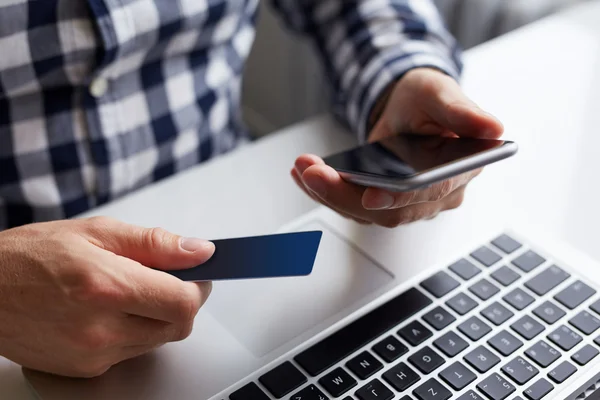 Homem com cartão de crédito e telefone ao pagar on-line — Fotografia de Stock