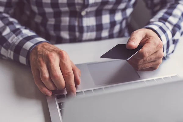 Człowiek z kartą w ręku i laptopa — Zdjęcie stockowe