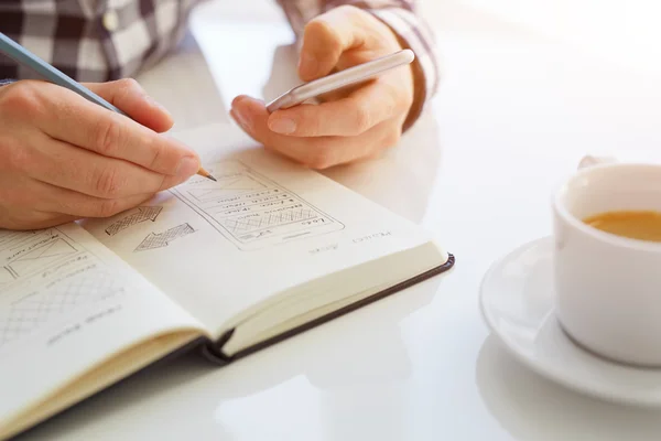 Man schetsen webdesign en het bedrijf van de mobiele telefoon. Getinte afbeelding met zonlicht — Stockfoto